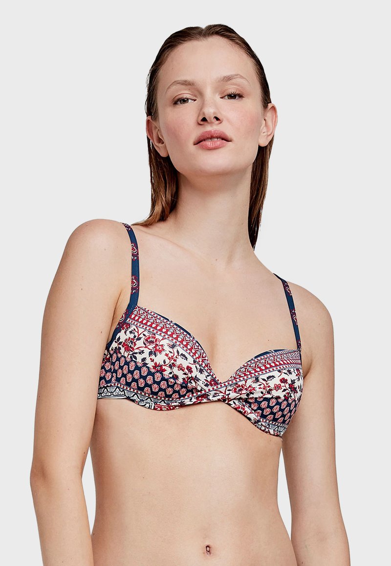 Reggiseno con ferretto caratterizzato da un motivo floreale nei toni blu navy, rosso e bianco, con spalline regolabili e un design frontale attorcigliato. Tessuto morbido.