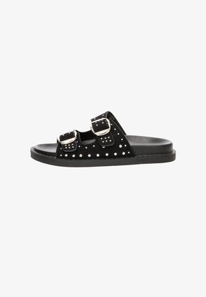 Sandalia tipo slide negra con dos hebillas plateadas ajustables y tachuelas plateadas en las correas y el borde de la suela. Suela plana y diseño de punta abierta.