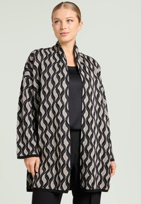 Lange, open voorkant cardigan in beige en zwart met een golfpatroon. Gemaakt van gestructureerde stof met lange mouwen en een losse pasvorm.