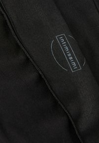 Schwarzer Stoff mit glatter Textur, der einen sichtbaren Reißverschluss und ein bedrucktes Markenlabel in Weiß aufweist. Das Design ist minimalistisch und elegant.