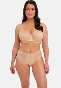 Ensemble de soutien-gorge beige et culotte taille haute en tissu texturé. Le soutien-gorge est doté de renforts à armature et de bretelles réglables, la culotte a une taille lisse.