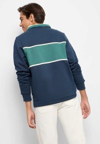 Felpa navy con striscia verde e accento bianco, caratterizzata da un colletto e maniche lunghe. Tessuto liscio e vestibilità comoda.