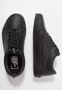 Sneaker nere in pelle con punta arrotondata, chiusura con lacci, pannelli laterali testurizzati e suola in gomma. Presenta il logo Vans sulla linguetta.