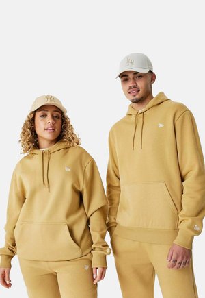 Haut à capuche kaki et pantalon de survêtement assorti en tissu doux, comportant des poches avant et des accents de logo sur le vêtement et la casquette.