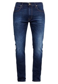 Jean slim bleu foncé avec poches avant et arrière, fermeture par boutons et subtils détails de décoloration sur les cuisses et les genoux.
