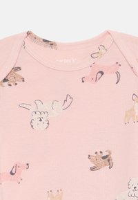 Ružový bavlnený overal s rôznymi ilustráciami psov v čiernej, béžovej a bielej farbe, so mäkkou textúrou a zaobleným výstrihom.