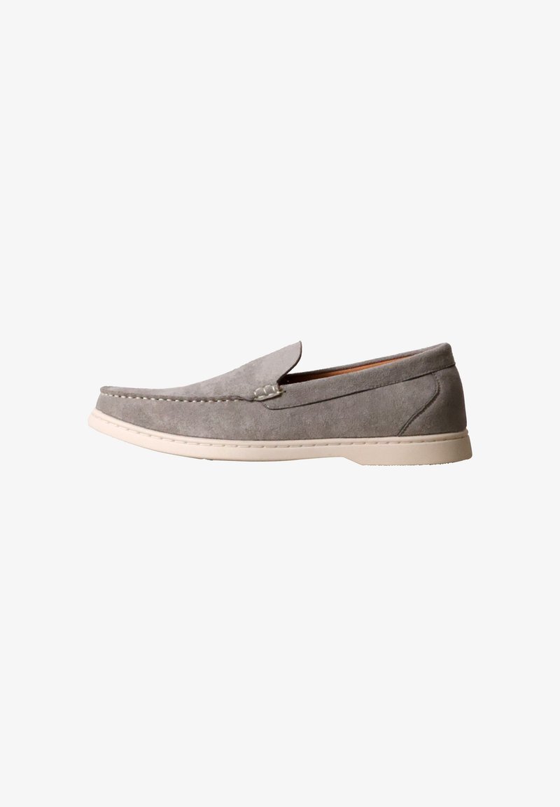 Mocassin en daim gris sans lacets avec semelle en caoutchouc blanche et détails cousus, présenté en profil sur fond blanc.