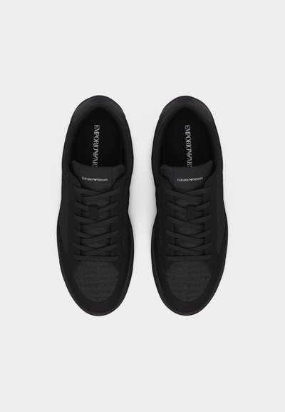 Ζευγάρι μαύρα sneakers Emporio Armani με κορδόνια, με επενδύσεις εσωτερικά με το λογότυπο της εταιρείας και διακριτικά μοτίβα λογότυπου στην περιοχή των δακτύλων, εμφανιζόμενα από πάνω σε λευκό φόντο.