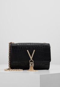 Borsa nera con texture a coccodrillo, dotata di tracolla in catena dorata, caratterizzata da un prominente logo "V" dorato e dettagli con frange decorative.