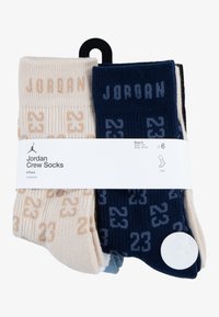 Calzini Crew Jordan 6 pezzi, disponibili in colori beige e blu navy con texture a coste. Ogni calzino presenta la scritta "JORDAN" e un design a motivi del numero "23".