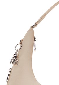 Beige læderhåndtaske med en buet design, prydet med sølv hardware og en lille metalcharms hængende fra en ring.