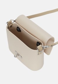 Borsa a tracolla color crema realizzata in pelle liscia, con patta arrotolabile, dettagli in metallo argentato e tracolla regolabile. L'interno mostra i dettagli dei compartimenti.