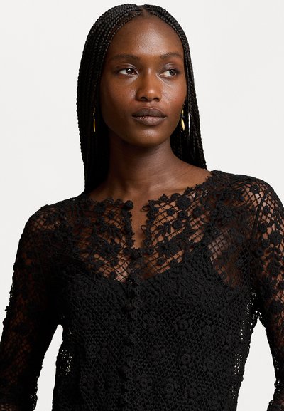 Black lace blouse featuring floral patterns, a deep V-neck with buttons, and long sleeves. The texture is intricate and layered.