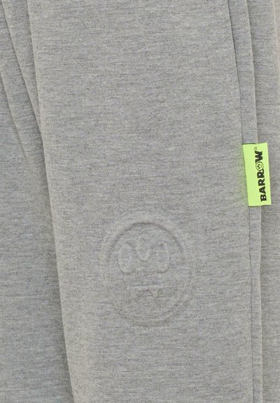 Szare spodnie dresowe wykonane z miękkiego materiału, z subtelnym wytłoczonym logo i jaskrawo zieloną metką dla kontrastu.