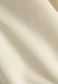 Blødt kremstof med en fin, tekstureret vævning. Let strakt, viser glatte, subtile variationer i farve og dybde.