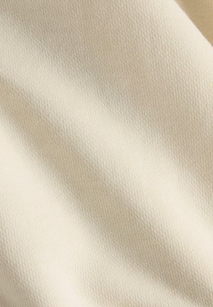 Zachte crèmestof met een fijne, gestructureerde weving. Licht uitgerekt, met zachte, subtiele kleur- en dieptevariaties.