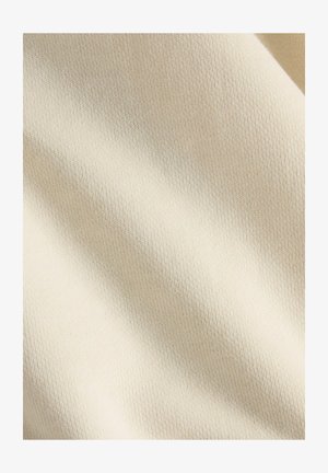 Tela de crema suave con un tejido fino y texturizado. Ligeramente estirada, mostrando variaciones suaves y sutiles en el color y la profundidad.