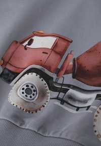 Illustrazione di un camion mescolatore di cemento rosso stampata su tessuto grigio, che mostra la cabina, le ruote e il tamburo di miscelazione.