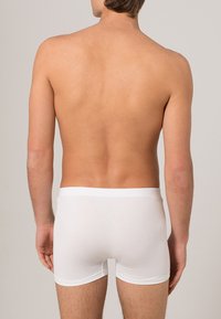Vita bomull boxershorts visade från baksidan. Har en slät midjeband och en åtsittande design som formar sig efter kroppen.