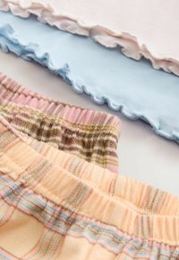 Trei perechi de pantaloni scurți decorativi: roz cu talie volanată, albastru deschis cu margini ondulate și în carouri cu elastic moale.