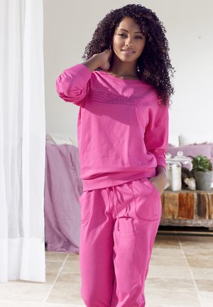 Pink sweatshirt with long sleeves and matching sweatpants. Simple design with text on the front, soft fabric, and relaxed fit.