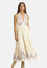 Ein cremefarbenes Halfterkleid mit lila bestickten Blumenmustern, einem taillierten Oberteil und einem fließenden, gestuften Saum.