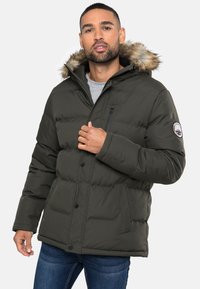 Dikke groene parka jas met een met bont gevoerde capuchon, voorzien van een ritszak op de borst, knopen en zakken aan de zijkanten. Casual stijl met een gewatteerd design.