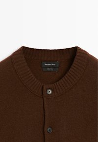 Brauner Wollcardigan mit einem gerippten Rundhalsausschnitt, einer knopfartigen Vorderseite mit zwei schwarzen Knöpfen und einer weich strukturierten Oberfläche.