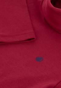 Burgunderfarget sweatshirt med en myk bomullstekstur, som har en foldet halsringning og en liten marineblå logo-detalj foran.