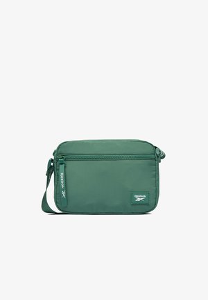 Bolso bandolera rectangular verde con bolsillo frontal con cremallera, correa ajustable y parche con el logo de Reebok y tirador de cremallera.