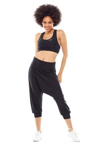 Bralette atlético negro y pantalones harem, hechos de una tela liviana. Los pantalones cuentan con puños gatherados y una cintura ancha para mayor comodidad.