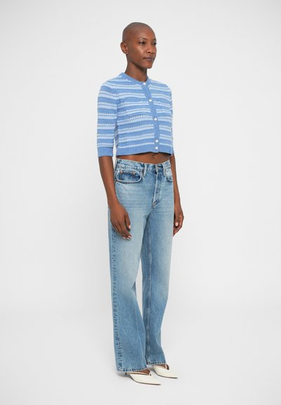 Cardigan court bleu clair avec des rayures horizontales, fermeture à boutons et poignets côtelés, associé à un jean droit taille haute en denim bleu délavé.