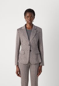 Tailored suit in patterned fabric, featuring a fitted blazer with a lapel, single button closure, and matching slim fit trousers.