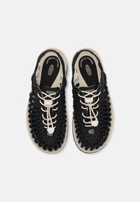 Black, breathable shoes with woven upper, contrasting beige sole, lace-up closure, and anatomical footbed for comfort.