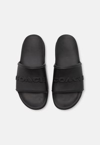 Black rubber slide sandals with two wide straps featuring embossed "COACH" branding. Smooth texture and rounded shape.