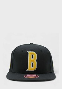 Musta baseball-lippis, jossa on suuri keltainen kirjailtu "B" etupuolella, suora lippa ja vaaleanpunainen bränditarrakiinnike lipassa.