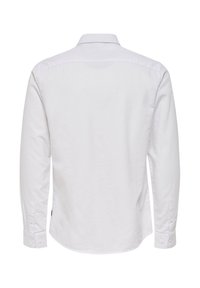 Camisa blanca de manga larga con cuello clásico, que presenta una textura suave, puños con botones y un corte recto en la parte trasera.
