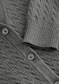 Grau gestrickte Strickjacke mit einem Zopfmuster, gerippten Bündchen und abgerundeten, dunklen Knöpfen mit "Clarks"-Markenlogo.