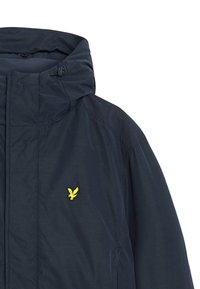 Mörkblå jacka med huva, med en gulbroderad logotyp på bröstet. Materialet verkar slätt och lätt.