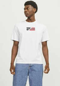 Hvid bomulds t-shirt med et sort, rødt og hvidt logo "JACK & JONES" på brystet. Korte ærmer og et klassisk fit design.
