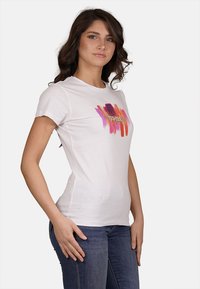 T-shirt bianca in cotone con design di pennellate multicolori e la scritta "YES ZEE" al centro. Maniche corte e scollo rotondo.