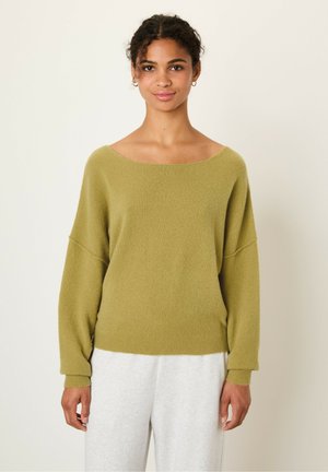 Olive green oversized sweater made of soft, textured fabric, features a wide neckline and wide sleeves, paired with light gray bottoms.