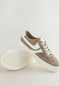 Brune ruskinds sneakers med hvide tekstildetaljer og snørebånd. De har en struktureret hvid gummisål med et geometrisk mønster.