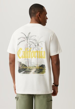 Biała koszulka z krótkim rękawem z pastelową ilustracją palm i krajobrazu, z napisem "California" w żółtym, pogrubionym foncie.