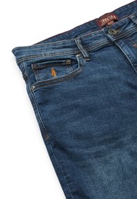 Blugi din denim albastru închis cu buzunar frontal având cusături maro și o mică figură brodată lângă eticheta de la talie.