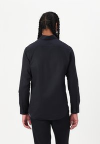 Black long-sleeve shirt with a straight hem, button cuffs, and a classic collar. Smooth fabric with a sleek, minimalist design.