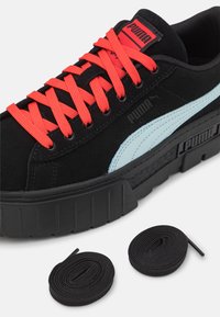 Sneaker in suede nero con striscia blu chiaro, suola in gomma nera e lacci rossi brillanti. Inclusi due lacci neri aggiuntivi.