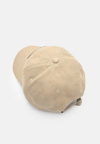Cappello in corduroy beige con visiera curva, design a sei pannelli e cinturino regolabile sul retro. Presenta un tessuto testurizzato e accenti cuciti.
