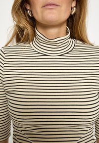 Pruhovaný rolákový top v krémovej a čiernej farbe s rebrovanou textúrou, krátkymi rukávmi, vysokým golierom a horizontálnymi pruhmi.