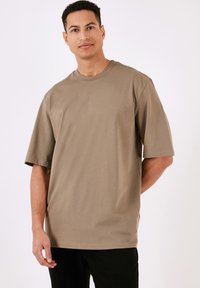 Khaki bavlněné tričko s kulatým výstřihem, krátkými rukávy a volným střihem. Hladká textura a jednoduchý design bez viditelných vzorů či akcentů.